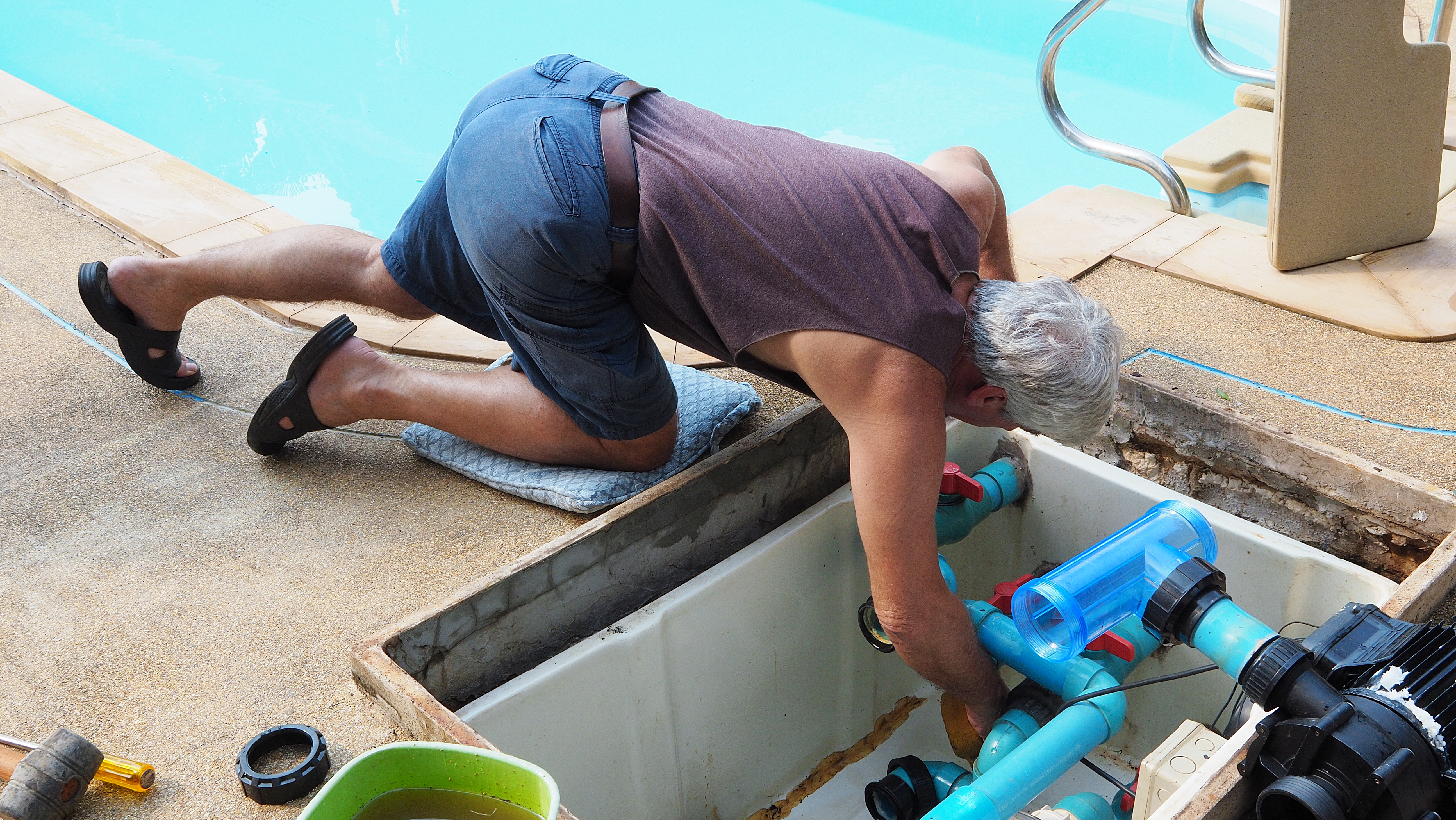 a man finding a leak in an inground pool pipe